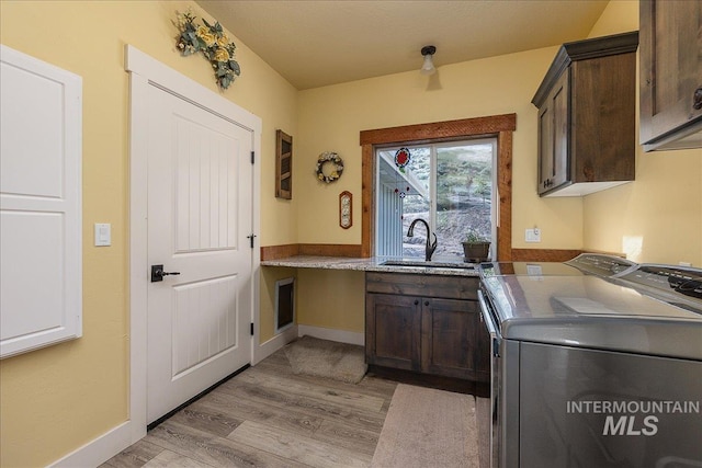 laundry area featuring light hardwood / wood-style flooring, sink, washer and clothes dryer, and cabinets