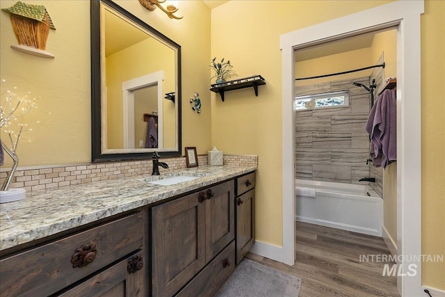 bathroom with vanity, hardwood / wood-style flooring, decorative backsplash, and tiled shower / bath combo