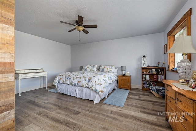 bedroom featuring ceiling fan, hardwood / wood-style floors, and a textured ceiling