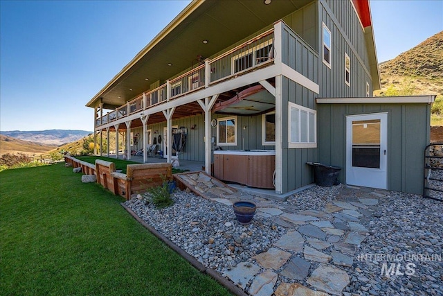 exterior space with a yard, a hot tub, a mountain view, and a patio