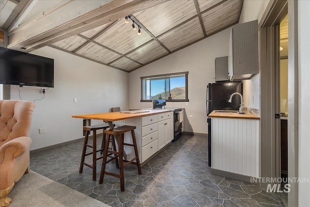 kitchen with wood counters, lofted ceiling, sink, black appliances, and white cabinets