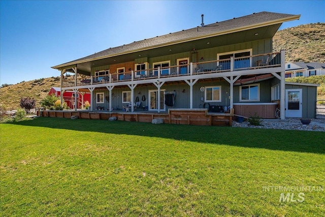 back of house featuring a balcony and a lawn