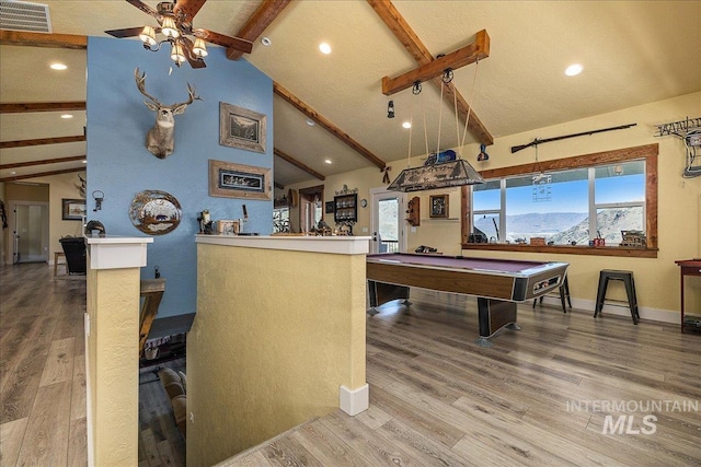 game room with a mountain view, wood-type flooring, lofted ceiling with beams, and plenty of natural light