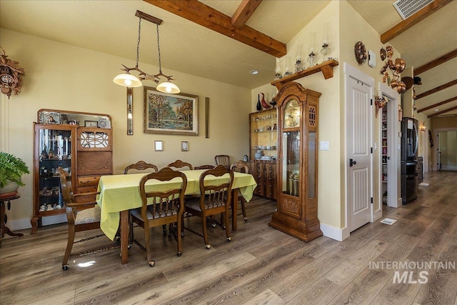 dining area featuring vaulted ceiling with beams and hardwood / wood-style floors