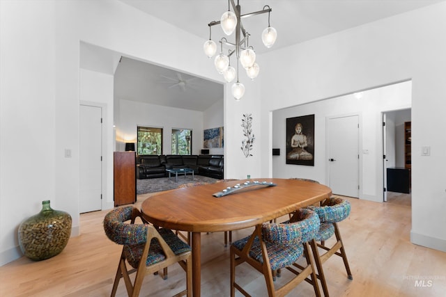 dining area featuring high vaulted ceiling, ceiling fan with notable chandelier, and light wood-type flooring