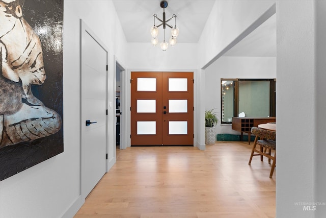 foyer featuring a notable chandelier, light hardwood / wood-style floors, and french doors