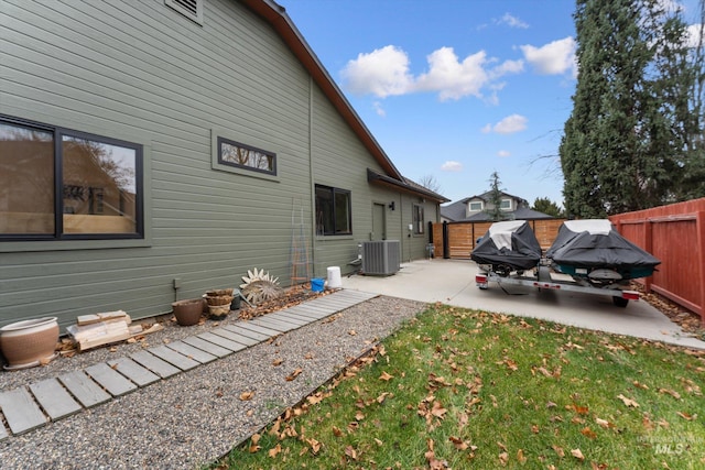 view of side of home featuring a patio, central AC, and a lawn