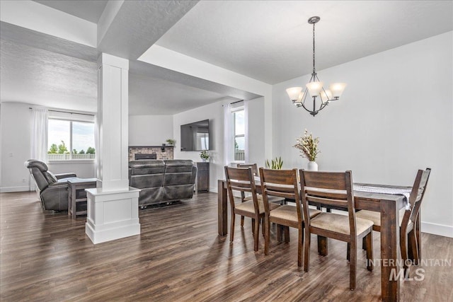 dining area with a chandelier, dark wood-type flooring, baseboards, and decorative columns