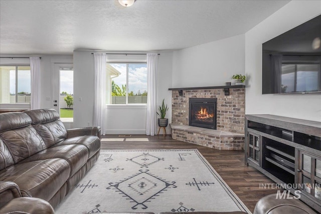 living room featuring a fireplace, a textured ceiling, and wood finished floors