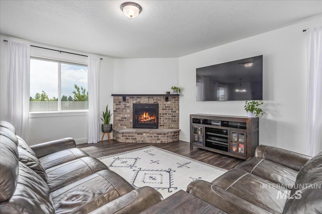 living room with a fireplace, wood finished floors, baseboards, and a textured ceiling