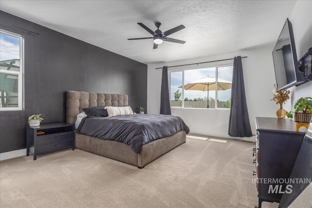 bedroom featuring light carpet, ceiling fan, a textured ceiling, and baseboards