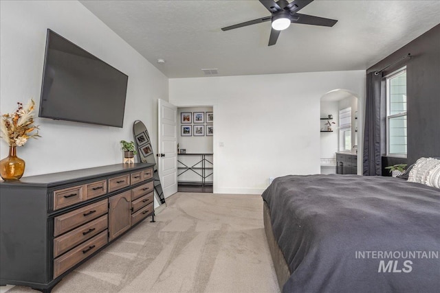 bedroom featuring baseboards, visible vents, arched walkways, and light carpet