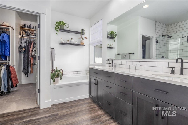 full bathroom with double vanity, a shower stall, wood finished floors, and a sink