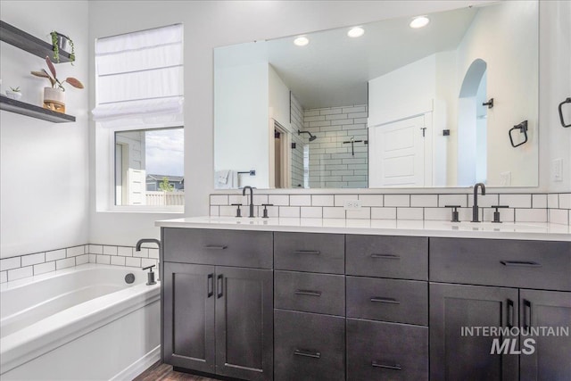 bathroom featuring a sink, a stall shower, a bath, and double vanity