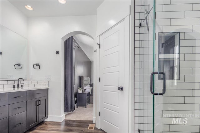 bathroom with wood finished floors, recessed lighting, a shower stall, baseboards, and vanity