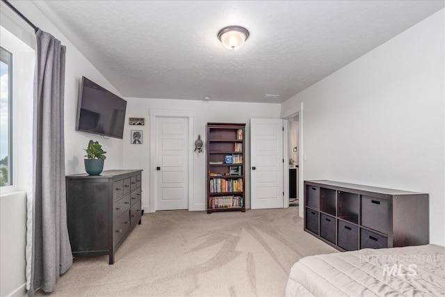 bedroom with multiple windows, light colored carpet, and a textured ceiling