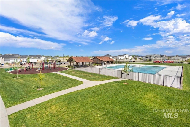 community pool with a yard, a residential view, playground community, and fence