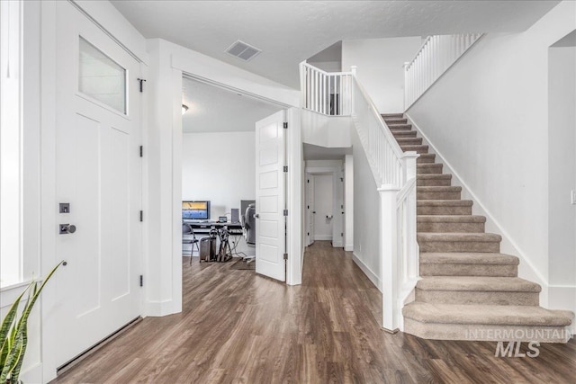 entryway with visible vents, baseboards, wood finished floors, and stairs