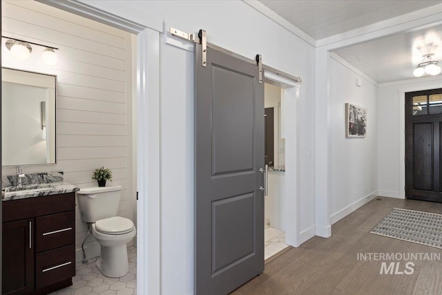2895 Evening Sun Dr, Twin Falls, ID 83301 - foyer featuring a barn door, light wood-style floors, ornamental molding, baseboards, and wood walls