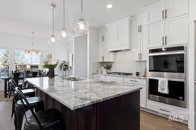 2895 Evening Sun Dr, Twin Falls, ID 83301 - kitchen with appliances with stainless steel finishes, decorative backsplash, a sink, wood finished floors, and light stone counters