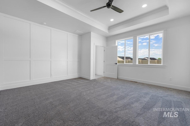 carpeted empty room featuring ceiling fan, a raised ceiling, and ornamental molding