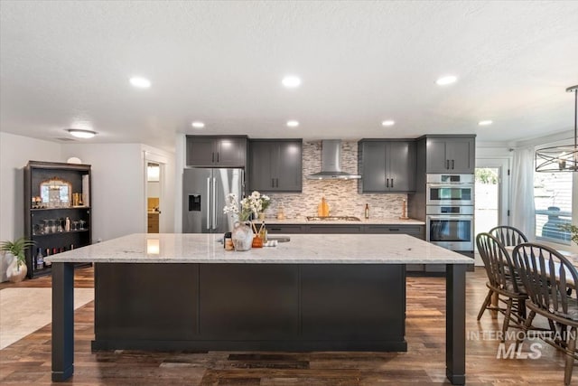 659 N Palmetto Dr, Eagle, ID 83616 - kitchen with wall chimney exhaust hood, a center island with sink, backsplash, light stone countertops, and appliances with stainless steel finishes