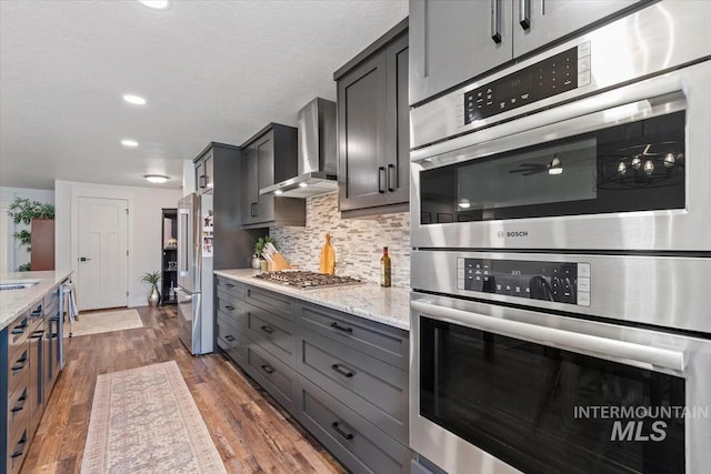 659 N Palmetto Dr, Eagle, ID 83616 - kitchen with dark wood finished floors, light stone counters, stainless steel appliances, backsplash, and wall chimney range hood