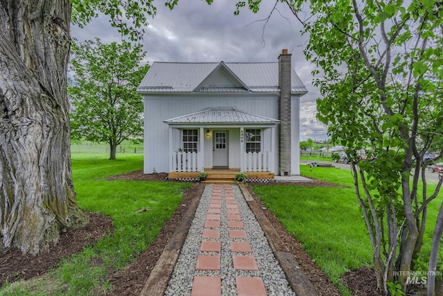 1304 Scott St, Grangeville, ID 83530 - view of front of house featuring covered porch, a chimney, board and batten siding, a front yard, and metal roof