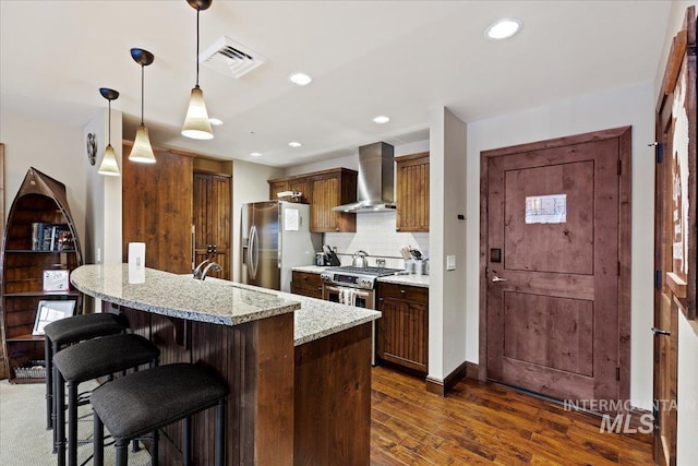 kitchen featuring wall chimney exhaust hood, decorative backsplash, decorative light fixtures, light stone counters, and stainless steel appliances