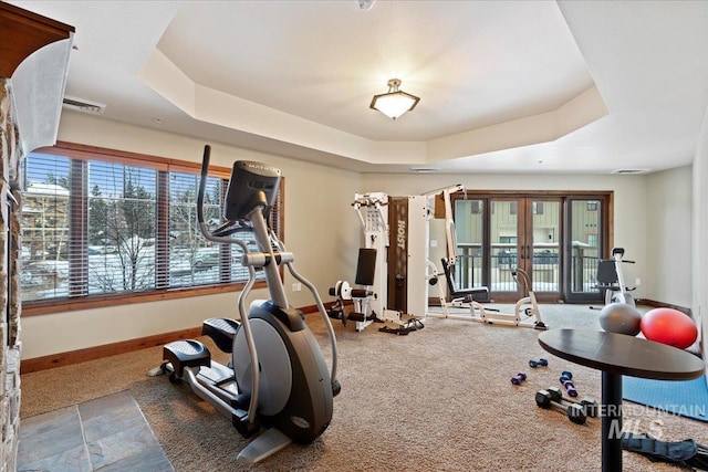 workout room with french doors and a raised ceiling