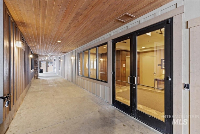 interior space with wooden ceiling, wooden walls, and concrete flooring