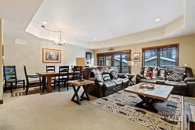 carpeted living room featuring a chandelier and a raised ceiling