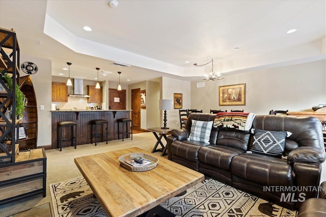 living room featuring light carpet, a raised ceiling, and a notable chandelier