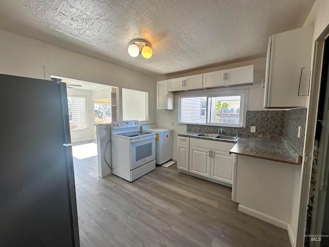 kitchen featuring white range with electric stovetop, white cabinets, a healthy amount of sunlight, and refrigerator