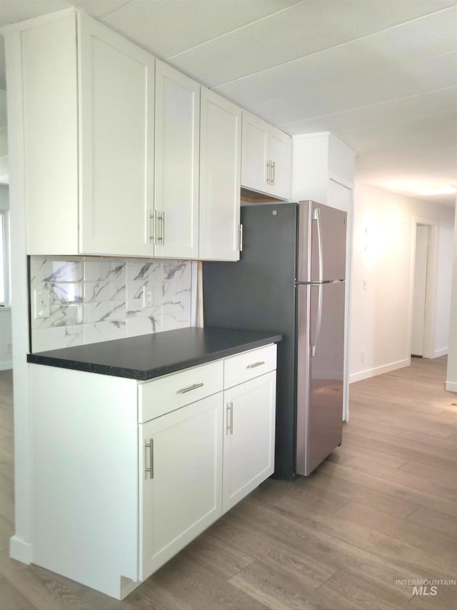 116 E 2nd St, Middleton, ID 83644 - kitchen featuring white cabinetry, backsplash, light wood-style floors, dark countertops, and freestanding refrigerator