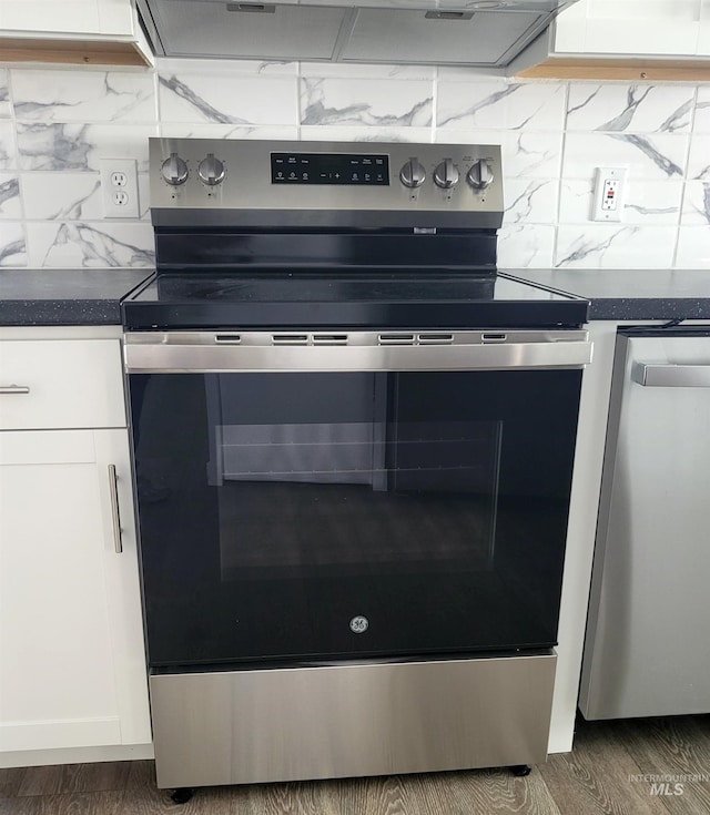 116 E 2nd St, Middleton, ID 83644 - kitchen view of stainless steel appliances, white cabinetry, decorative backsplash, dark countertops, and wood finished floors
