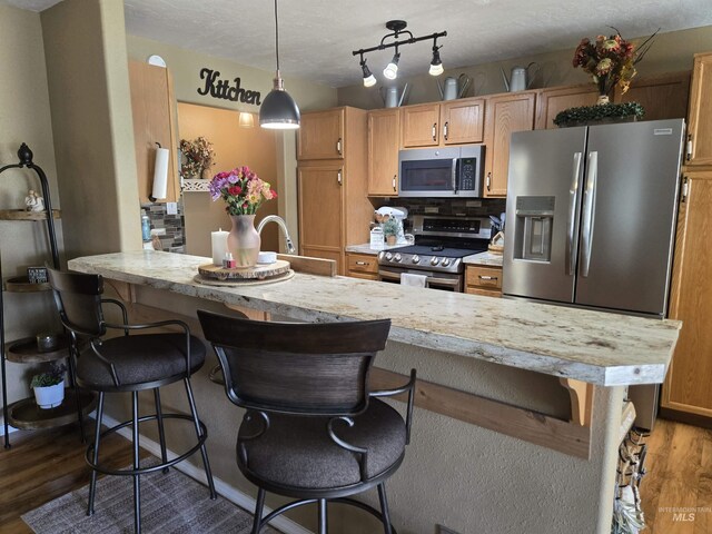 1451 Spurlock Ct, Twin Falls, ID 83301 - kitchen featuring stainless steel appliances, wood finished floors, a breakfast bar, tasteful backsplash, and a peninsula