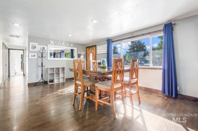 dining space with dark wood-style floors, a textured ceiling, visible vents, and baseboards