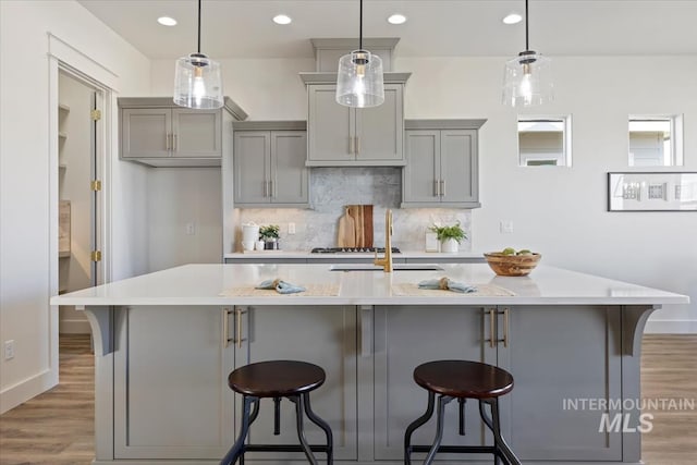 8820 E Snow Drop St, Nampa, ID 83687 - kitchen with a sink, light wood-style floors, baseboards, backsplash, and gray cabinetry