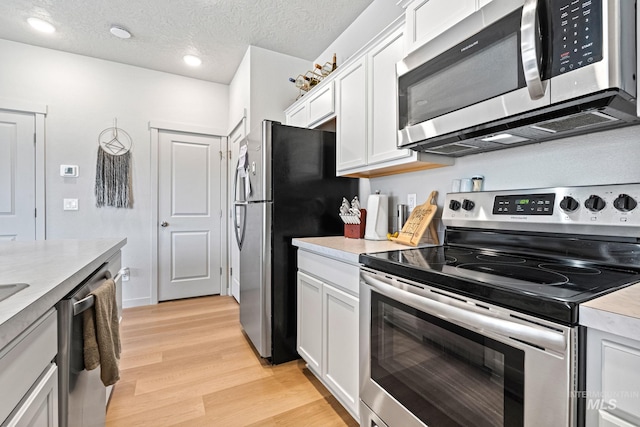 2312 E Spice Loop Unit 2, Nampa, ID 83687 - kitchen with stainless steel appliances, light wood-style flooring, light countertops, white cabinetry, and a textured ceiling