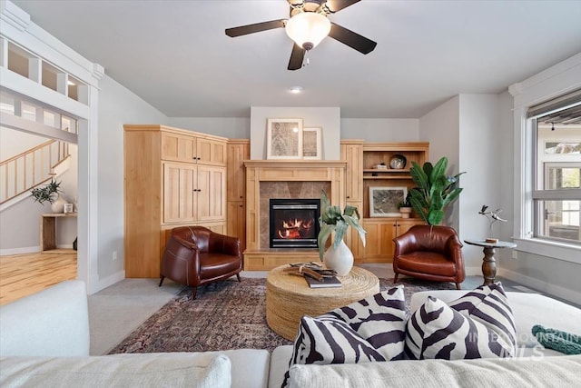 living area featuring baseboards, a ceiling fan, stairs, carpet floors, and a fireplace