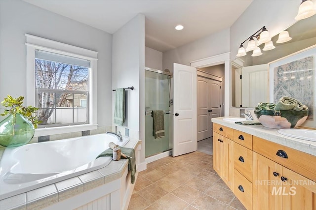 bathroom featuring double vanity, a stall shower, a bath, tile patterned floors, and a sink