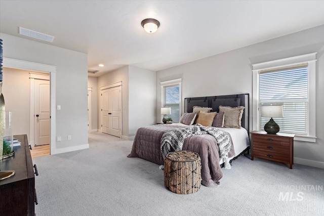 bedroom with light carpet, multiple windows, visible vents, and baseboards