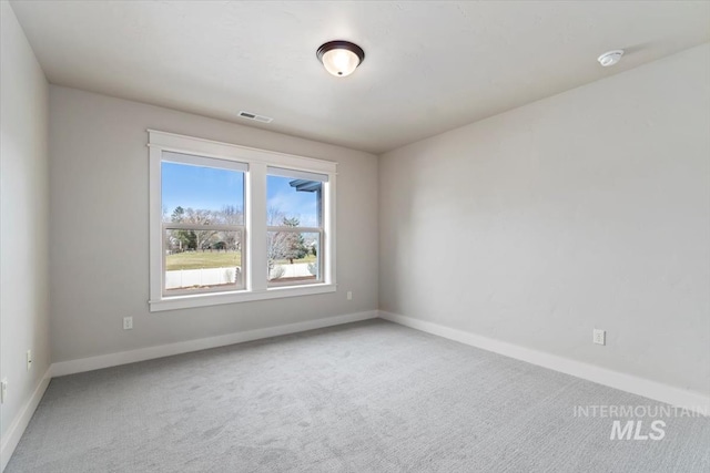 carpeted spare room featuring visible vents and baseboards