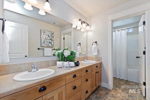 full bath featuring double vanity, visible vents, stone finish floor, and a sink