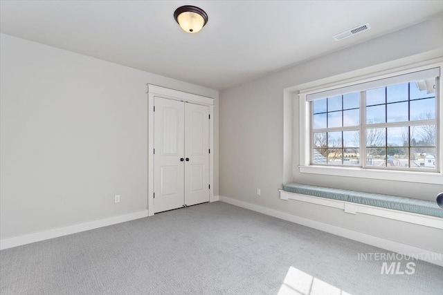 unfurnished bedroom featuring a closet, baseboards, visible vents, and carpet flooring