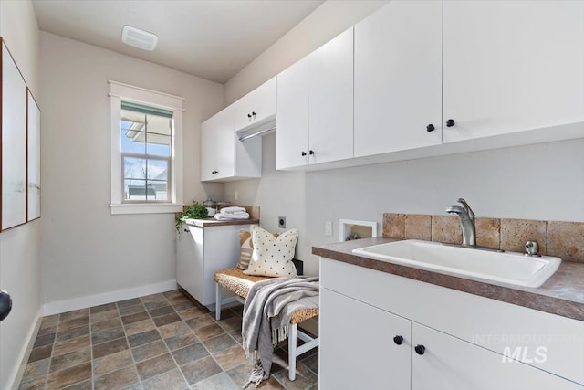 laundry area with washer hookup, cabinet space, a sink, electric dryer hookup, and baseboards