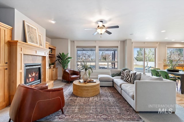 living area featuring a tile fireplace, a ceiling fan, and recessed lighting