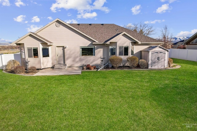 72 Pelican Dr, Rupert, ID 83350 - rear view of property featuring a lawn, a storage shed, fence, and an outbuilding