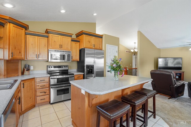 72 Pelican Dr, Rupert, ID 83350 - kitchen with light tile patterned floors, a kitchen bar, vaulted ceiling, stainless steel appliances, and open floor plan